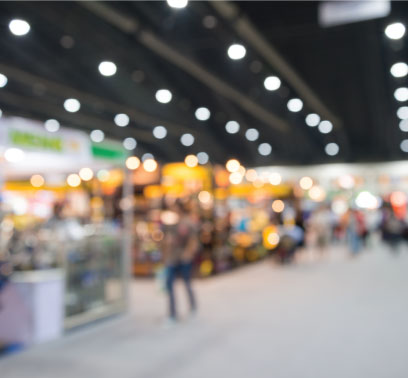 A blurred photo of people walking around a trade show.