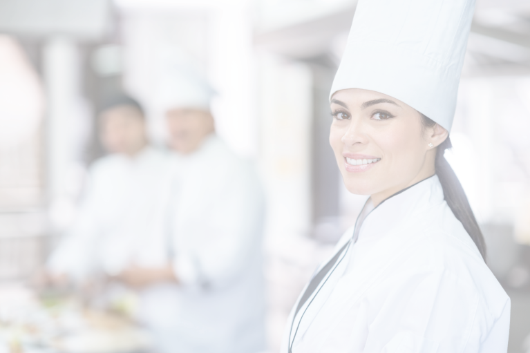 A female chef wearing a tall hat and smiling at the camera while working with hospital foodservice management software.