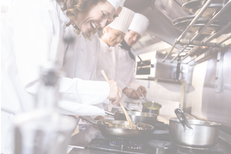 A line of chefs smile as they cook on stoves in an industrial hospital kitchen automated by foodservice management software.