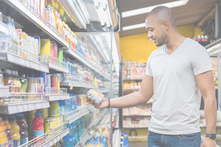 A profile shot of a man browsing refrigerated beverages in a store that uses nutrition labeling.